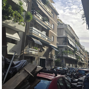 Apartment view in athens. Building has balconies. The street is full of cars and scooters.